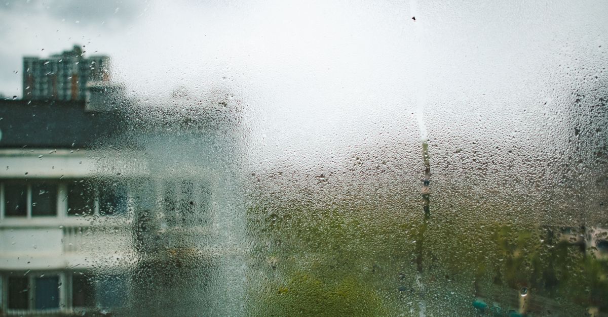 View of Shanghai buildings through a dewy, moisture-covered window during a cloudy day.